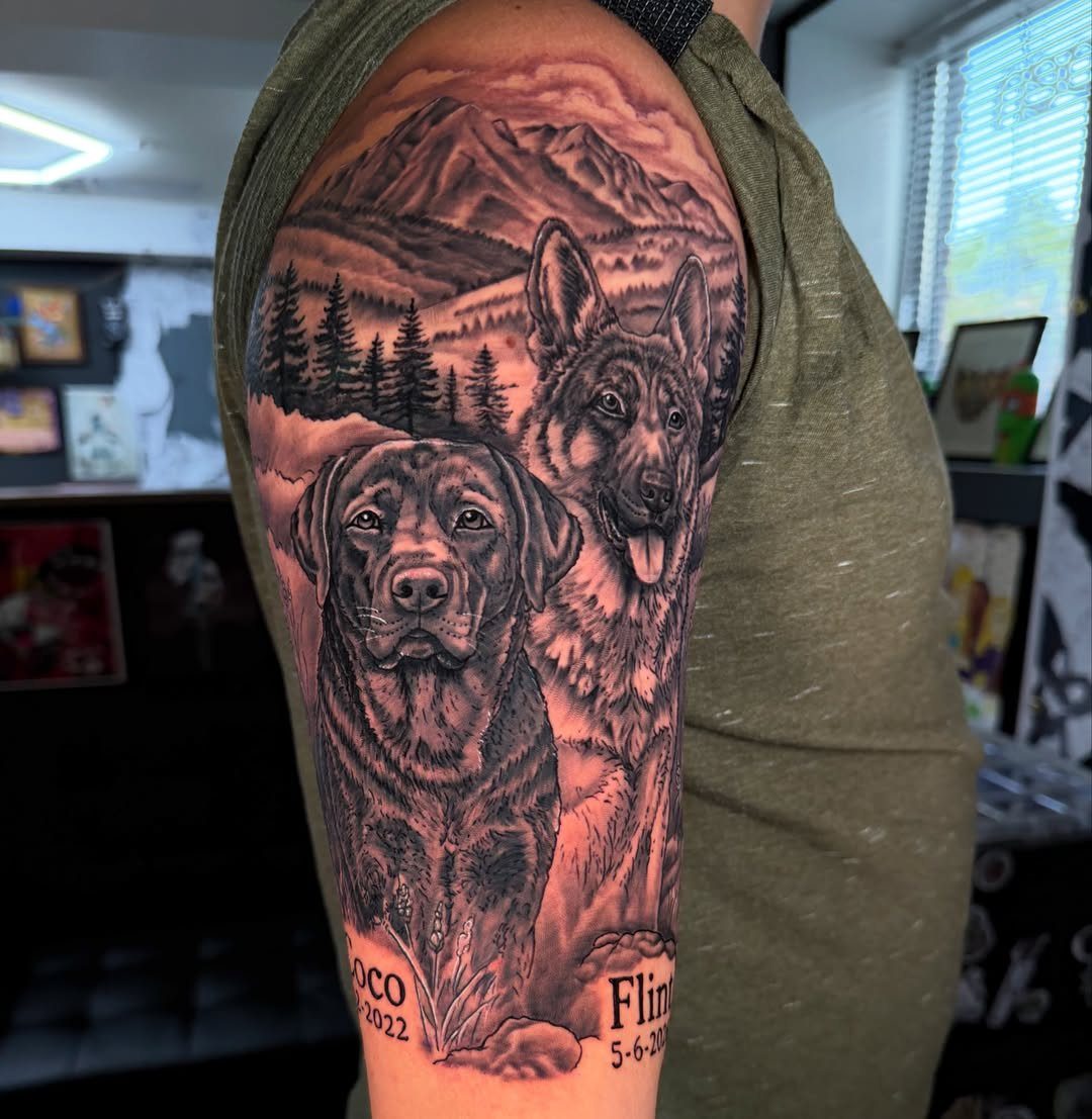 Tattoo of two dogs with mountains and pine trees on a person's arm