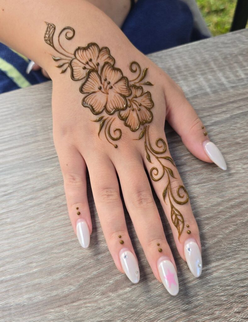 Henna tattoo of brown flowers and vines on the back of a hand