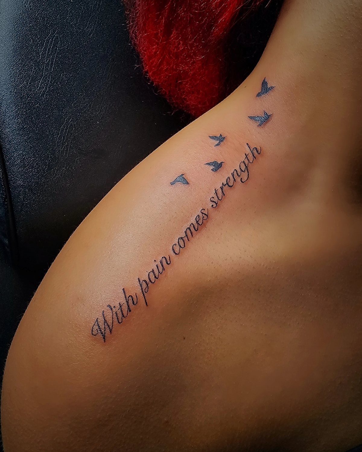 Tattoo on a shoulder with the phrase With pain comes strength and flying birds.