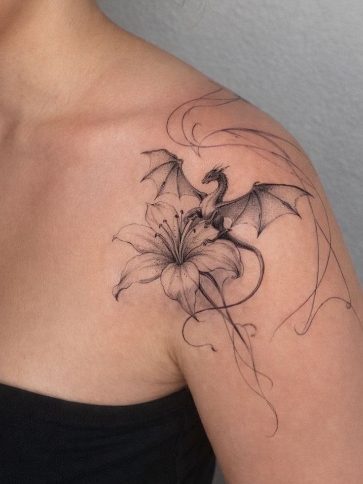 Dragon and lily flower tattoo with fine line swirls on a shoulder