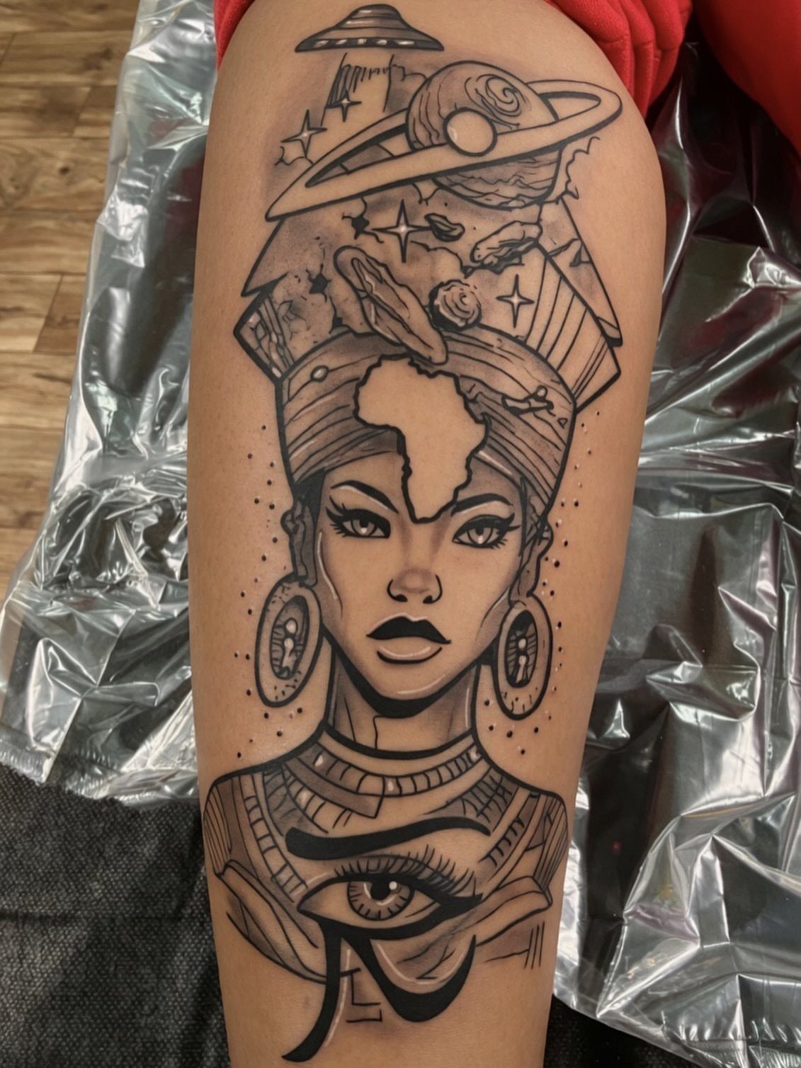 Black and grey tattoo of a woman with space elements on a leg