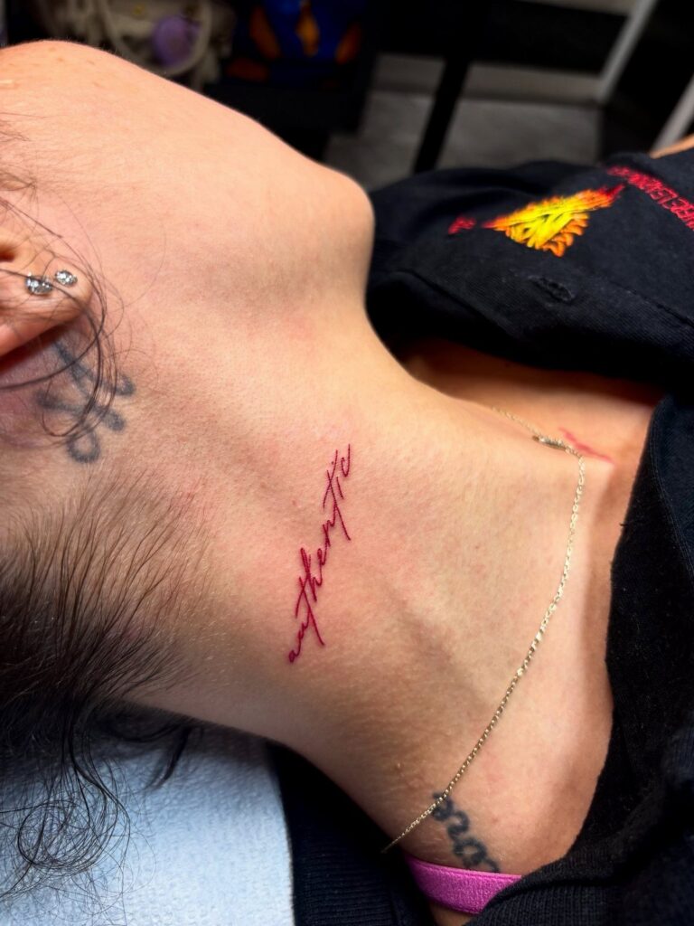 Red cursive word tattoo on the side of a person's neck