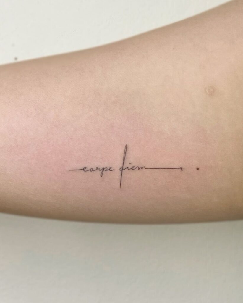 Small black script tattoo reading carpe diem on a person's inner bicep.