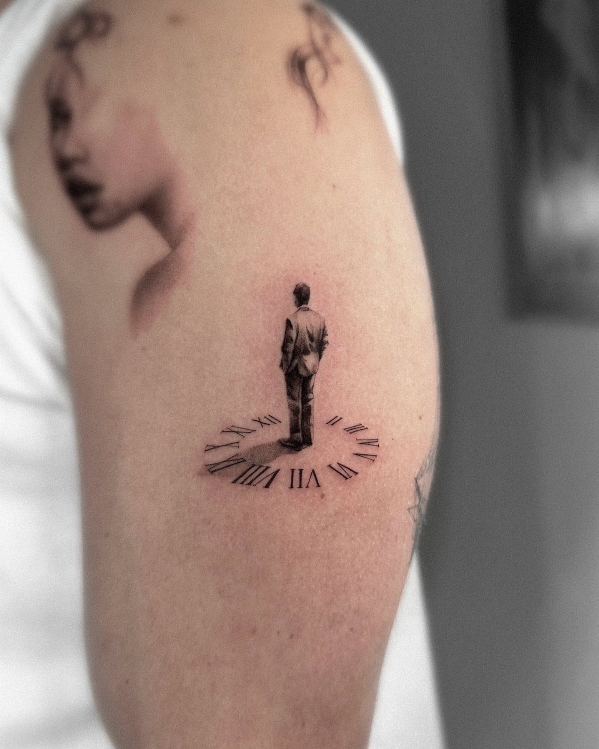 Tattoo on an arm showing a man standing on a Roman numeral clock face.