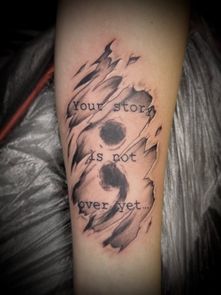 Semicolon tattoo on an arm with text saying Your story is not over yet