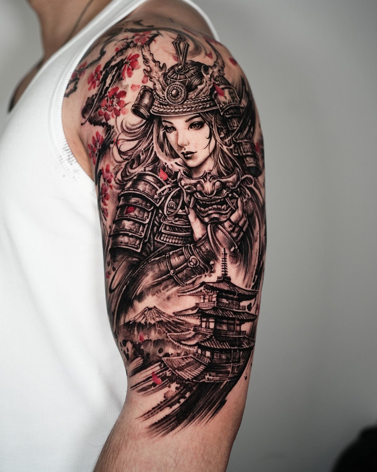 Female samurai warrior tattoo on an arm with cherry blossoms and a pagoda.
