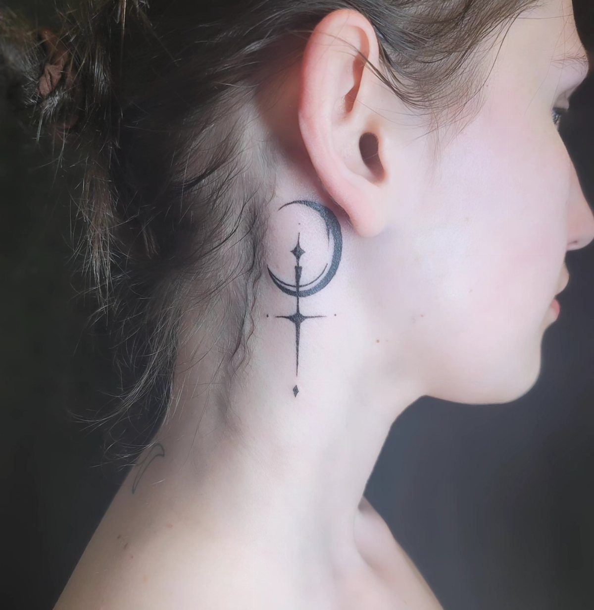 Crescent moon and celestial star tattoo on the side of a person's neck.